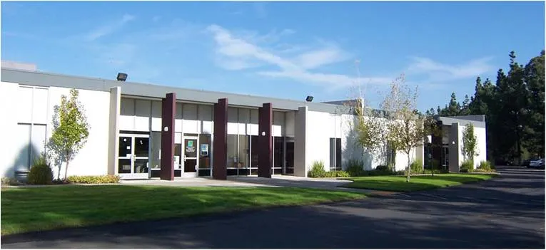 Lucent Optics headquarters at 1832 Tribute Road, Sacramento: a single-story white office building with dark red entrance columns and a front lawn