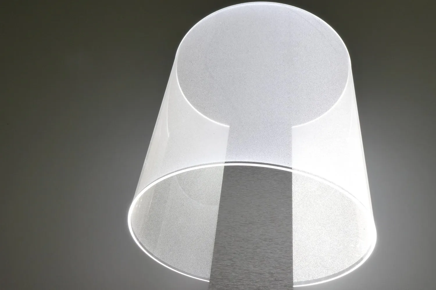 Lit CoreGLO wall sconce, a thin clear sheet curved into a glowing shade