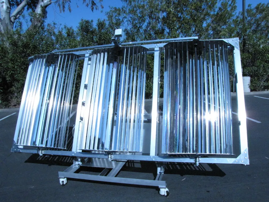 Portable solar appliance outdoors: three slat-array collector modules on a wheeled frame