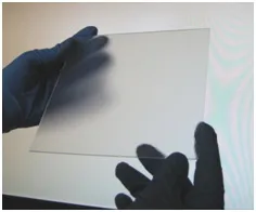 Prototype of the light-trapping laminate: a clear glass sheet held up in gloved hands