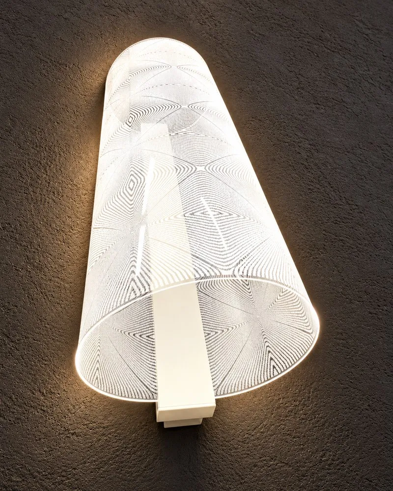 Tubular CoreGLO wall sconce with a geometric pattern of concentric diamonds, glowing warm white against a dark textured wall