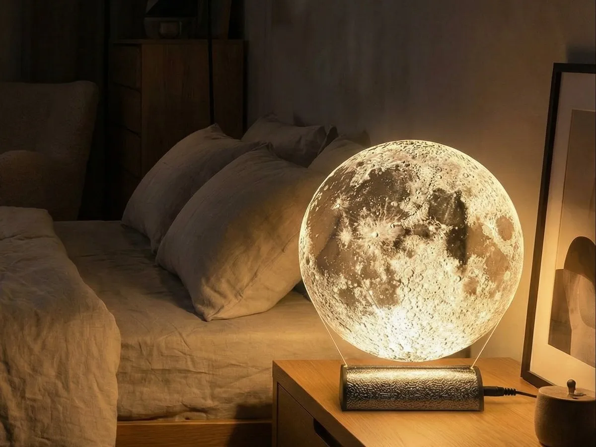 Moon Lamp glowing warm white on a bedside table in a dim bedroom