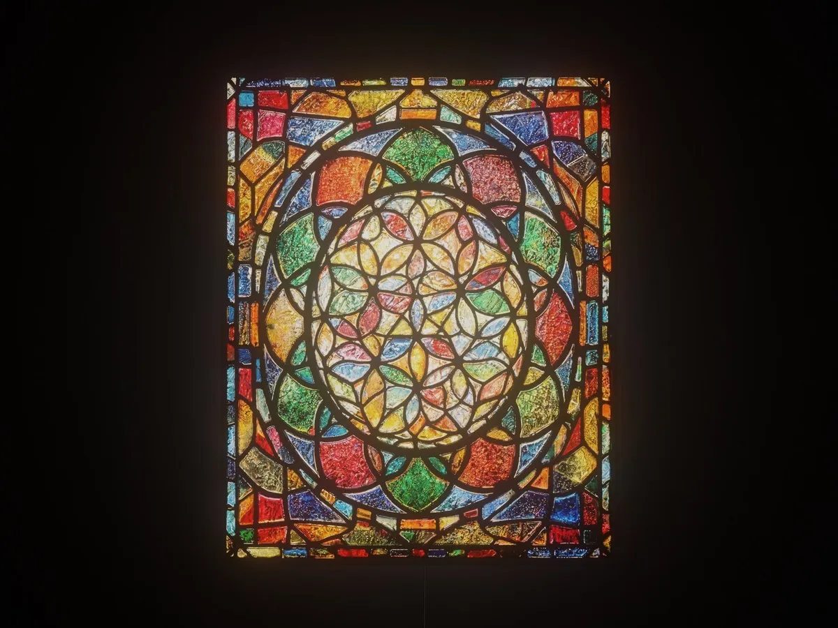 Flower of Life wall art in the style of colorful leaded stained glass, glowing on a dark wall