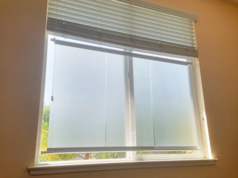 Home window covered by a translucent Luminyl™ shade below a raised venetian blind