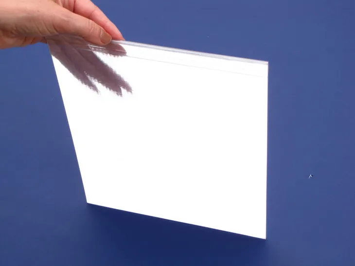 Hand holding a square, bright white Luminyl™ panel against a blue background