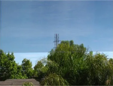 Residential window with the film installed: the film tints the bright sky in the upper part of the window